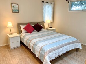 Una cama bien hecha con un edredón a rayas, dos lámparas de noche y dos almohadas sobre una mesita de noche.