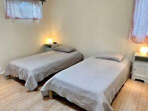 Dos camas individuales con cabeceras, mesitas de noche con lámparas y cortinas estampadas.