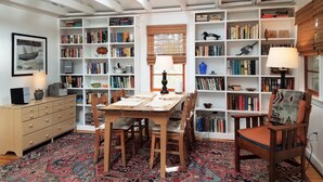 Eine gemütliche Leseecke mit einem Holztisch, Stühlen und einer Bücherwand voller Bücher.
