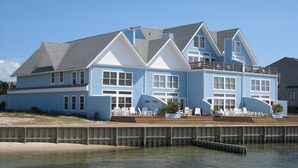 A large, two-story house with a flat roof, multiple windows, and a balcony.