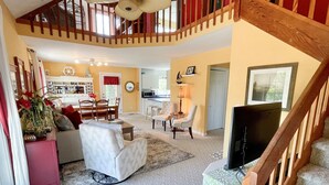 A spacious living area with a high ceiling, a dining table, and a kitchen in the background. - Nicely Secluded Home, Short Stays Allowed (Ocracoke)