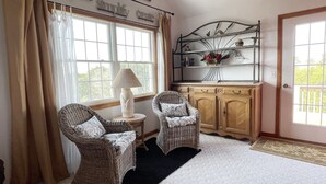 A cozy room with wicker furniture, a lamp, and a shelf with decorative items. - Nicely Secluded Home, Short Stays Allowed (Ocracoke)
