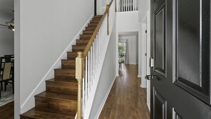 Una escalera de madera con barandillas blancas que sube a un segundo piso.