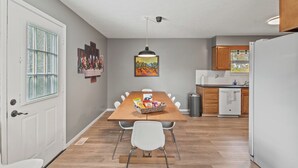 A dining area with a wooden table, white chairs, and a fruit basket. - 8 min to Ark, Playroom, Sleeps 12 on Quiet Street (Williamstown)