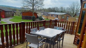 Une terrasse en bois avec une table et des chaises, une vue sur les environs et une clôture en bois.