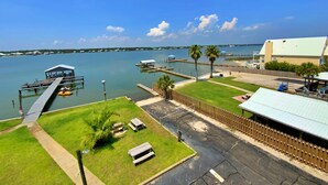 Um imóvel à beira-mar com um cais, mesas de piquenique e um edifício com telhado inclinado.