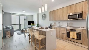 A modern kitchen with a central island, stainless steel appliances, and a dining area with wicker chairs.