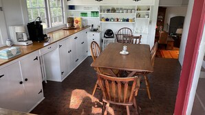 Een keuken met een houten tafel en stoelen, witte kastjes en een koffiezetapparaat.