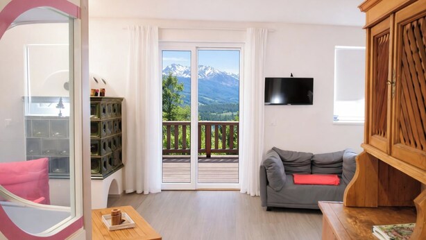 A room with a balcony, a grey sofa, a wooden cabinet, a TV, and a small table with a tray. - Casa 4 Pioppi - View and relaxation (Cavalese)