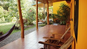 A covered patio with wooden furniture, a hammock, and a garden view.