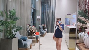 Una moderna hall d'albergo con un'area salotto, una reception e un grande specchio che riflette l'ambiente.