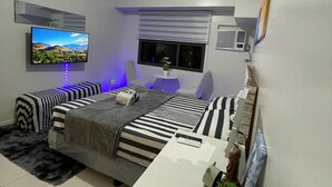 Una camera da letto moderna con un letto, comodini, una TV e una finestra con persiane.
