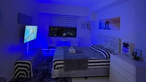 Camera da letto moderna con un letto grande, una TV e illuminazione a LED.