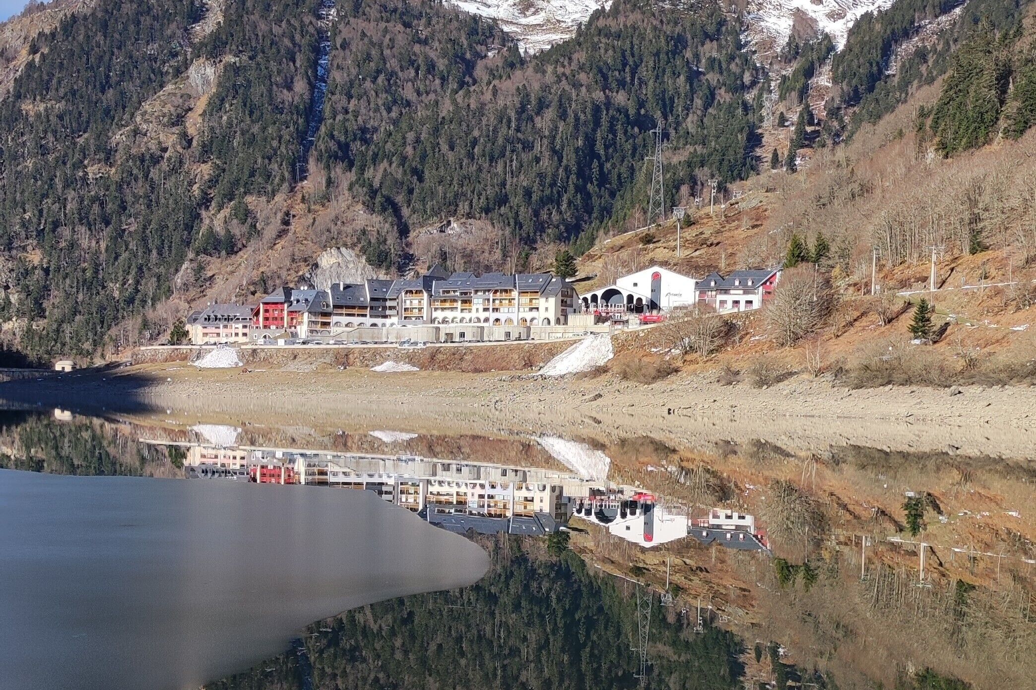 A hotel with multiple buildings, a parking area, and a lake reflecting the structures.