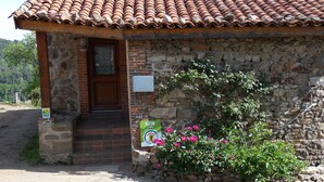 A rustic stone building with a tiled roof, a wooden door, and a small porch.