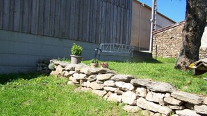 A stone wall, a small garden with a potted plant, and a metal gate.