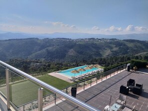 A rooftop pool with lounge chairs and umbrellas, surrounded by a scenic mountainous landscape. - Quinta da Corujeira (Vila Real)