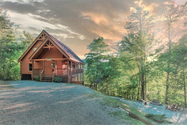 Une cabane en bois dotée d’un porche, entourée d’une forêt.