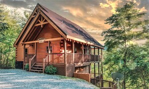 Une cabane en rondins dotée d’un balcon, d’une véranda et d’un escalier menant à l’entrée.