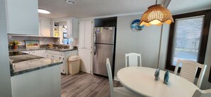 Kitchen area with a refrigerator, sink, and dining table near a window.