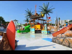 Enjoy thrilling water park fun with a green slide, yellow play structure, and red slide.