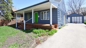 Une maison de plain-pied avec un porche à l’avant, une porte verte et un garage.