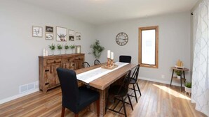 Un coin repas avec une table en bois, des chaises noires, un buffet en bois et des tableaux encadrés accrochés au mur.