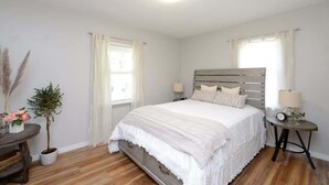 Une chambre à coucher avec un lit, des tables de chevet, une fenêtre et une plante.