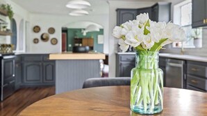 Una cocina moderna con armarios oscuros, una mesa de comedor de madera y un jarrón con flores blancas.