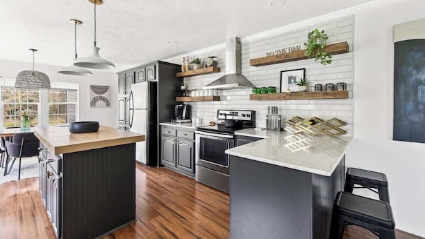 Una cocina moderna con una isla central, electrodomésticos de acero inoxidable y un salpicadero de ladrillo blanco.