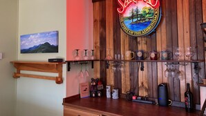 A bar area with a wooden backdrop, a neon sign reading "SARANAC", and various glassware and bottles. - Cozy, peaceful "camp" in Hollywood Hills, just north of the town of Old Forge (Old Forge)