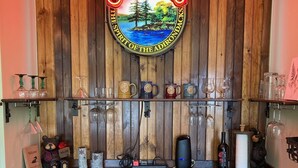 A kitchen counter with a neon sign reading "Saranac The Spirit of the Adirondacks," a refrigerator, and various kitchen items. - Cozy, peaceful "camp" in Hollywood Hills, just north of the town of Old Forge (Old Forge)
