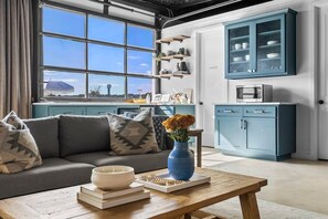 A modern living room with a sofa, a coffee table, and a view through large windows. - 10 Bedroom / Pool / Hot tub / Pickleball / Firepit (Dripping Springs)