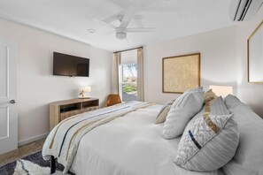 A hotel room with a bed, a desk, a chair, a television, and a window. - 10 Bedroom / Pool / Hot tub / Pickleball / Firepit (Dripping Springs)