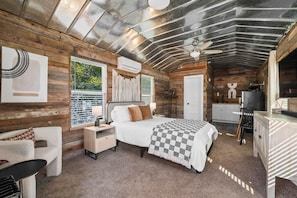 A cozy cabin-style bedroom with a bed, nightstands, a dresser, and a ceiling fan.