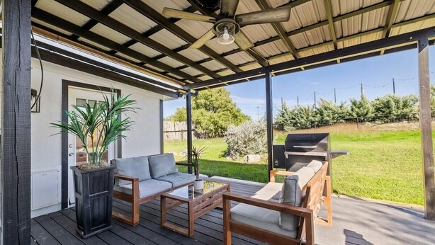A covered outdoor seating area with a sofa, two coffee tables, and a grill. - 10 Bedroom / Pool / Hot tub / Pickleball / Firepit (Dripping Springs)