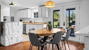 A modern kitchen with white cabinets, a stone island, and a dining area with a round table and chairs. - 10 Bedroom / Pool / Hot tub / Pickleball / Firepit (Dripping Springs)