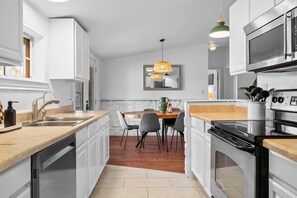 A modern kitchen with white cabinetry, a built-in oven, and a dining area with a table and chairs. - 10 Bedroom / Pool / Hot tub / Pickleball / Firepit (Dripping Springs)