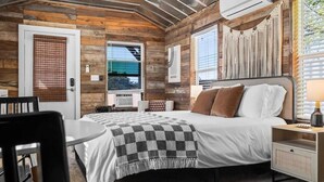 A bedroom with a bed, bedside table, and a window. - 10 Bedroom / Pool / Hot tub / Pickleball / Firepit (Dripping Springs)