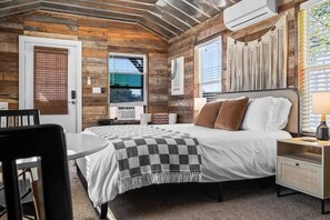 A bedroom with a bed, bedside table, and a window. - 10 Bedroom / Pool / Hot tub / Pickleball / Firepit (Dripping Springs)