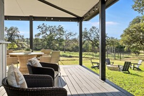 An outdoor patio with wicker furniture and a view of a grassy area. - 10 Bedroom | Pool | Hot tub | Pickleball | Firepit (Dripping Springs)