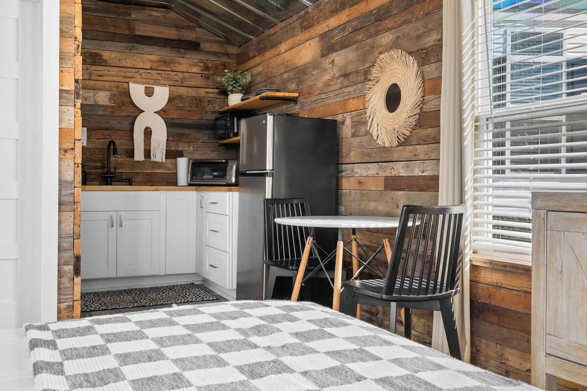 A compact kitchen with a refrigerator, microwave, and a small dining area with a table and chairs.