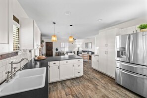 A modern kitchen with white cabinetry, a stainless steel refrigerator, and pendant lighting. - 10 Bedroom | Pool | Hot tub | Pickleball | Firepit (Dripping Springs)