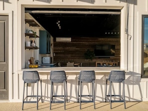 An outdoor bar area with four metal chairs and a counter. - 10 Bedroom / Pool / Hot tub / Pickleball / Firepit (Dripping Springs)
