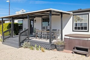 A covered outdoor seating area with a patio, a staircase, and a wooden deck. - 10 Bedroom / Pool / Hot tub / Pickleball / Firepit (Dripping Springs)