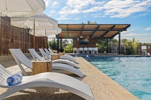 A poolside area with lounge chairs and umbrellas, a covered seating area, and a pool. - 10 Bedroom / Pool / Hot tub / Pickleball / Firepit (Dripping Springs)