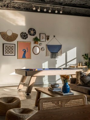 A cozy living room with a pool table, comfortable seating, and various wall decorations. - 10 Bedroom / Pool / Hot tub / Pickleball / Firepit (Dripping Springs)