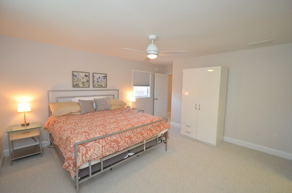 A bedroom with a bed, bedside tables, a ceiling fan, and a wardrobe.