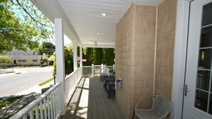 Eine überdachte Veranda mit weißem Geländer, einem weißen Stuhl und einer Tür mit Fenster.