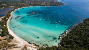 Vue aérienne d’une zone côtière avec des eaux turquoise limpides, des bateaux et une plage.